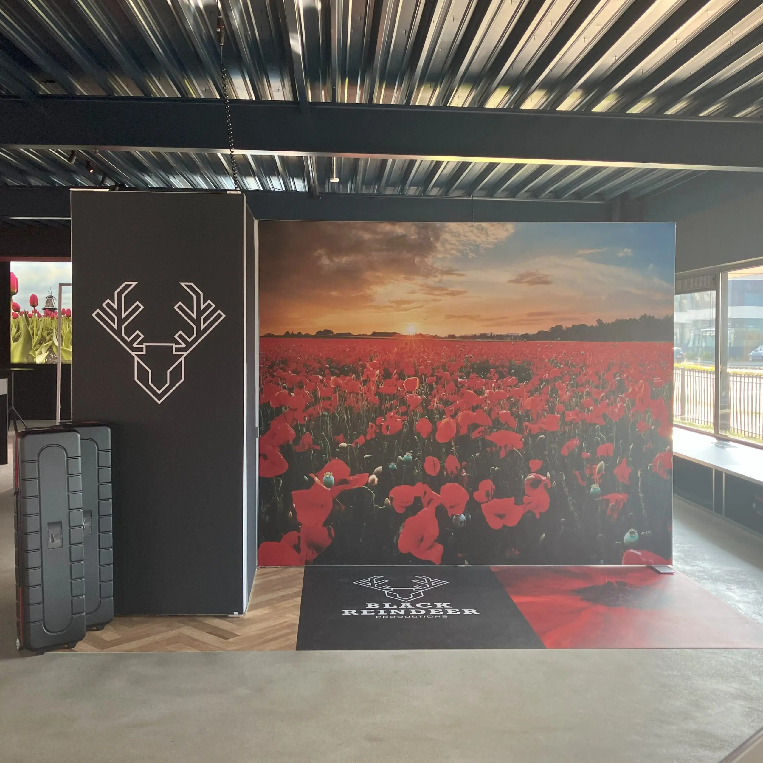 Beurswand met grote full colour print van een bloemenveld en zwart paneel met logo voor een opvallende merkpresentatie op locatie.