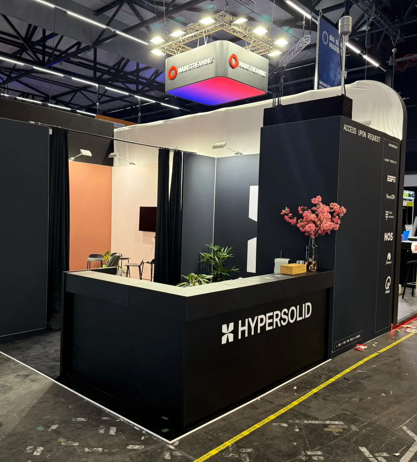 Zwarte beursstand van Hypersolid met grote balie, merkuitingen en zitgedeelte voor een professionele presentatie op de beurs.